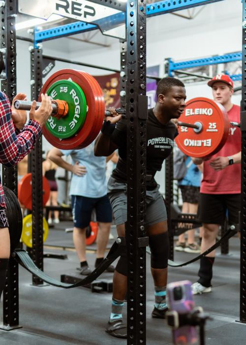 Powerlifter squatting heavy weight with spotters